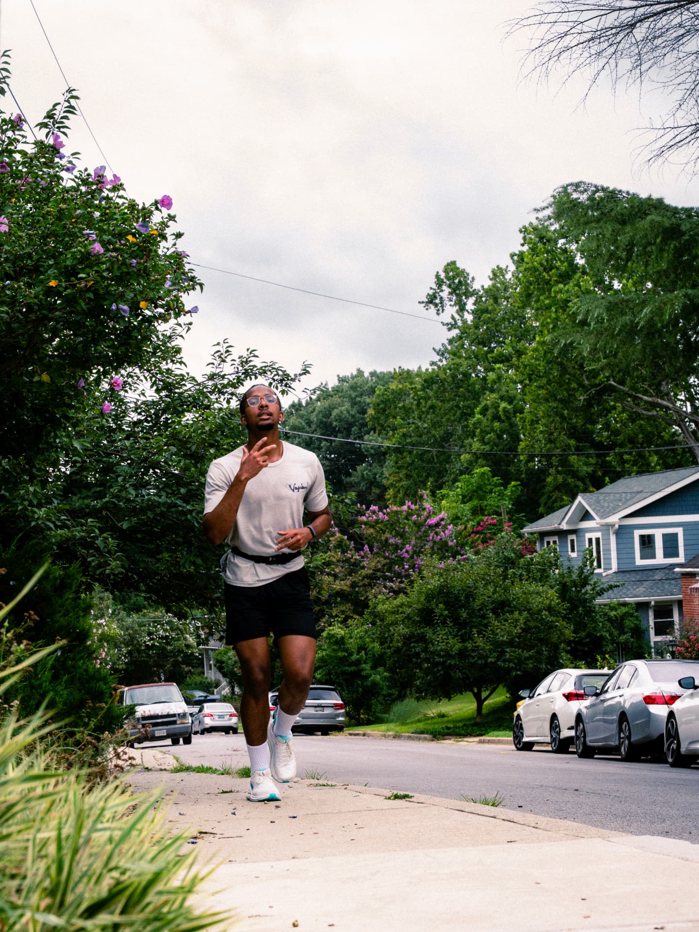 A runner in glasses and a white tee on the sidewalk