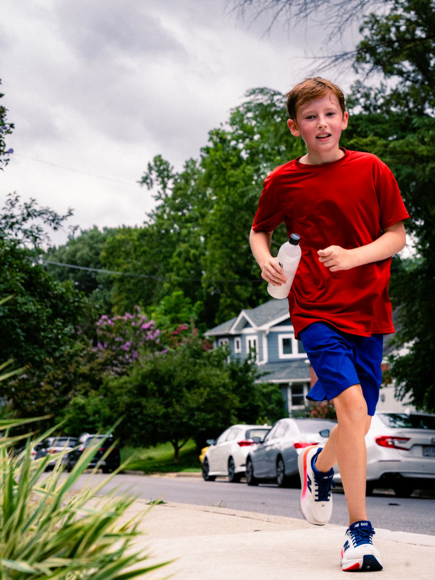 A young runner in red pushing up the sidewalk