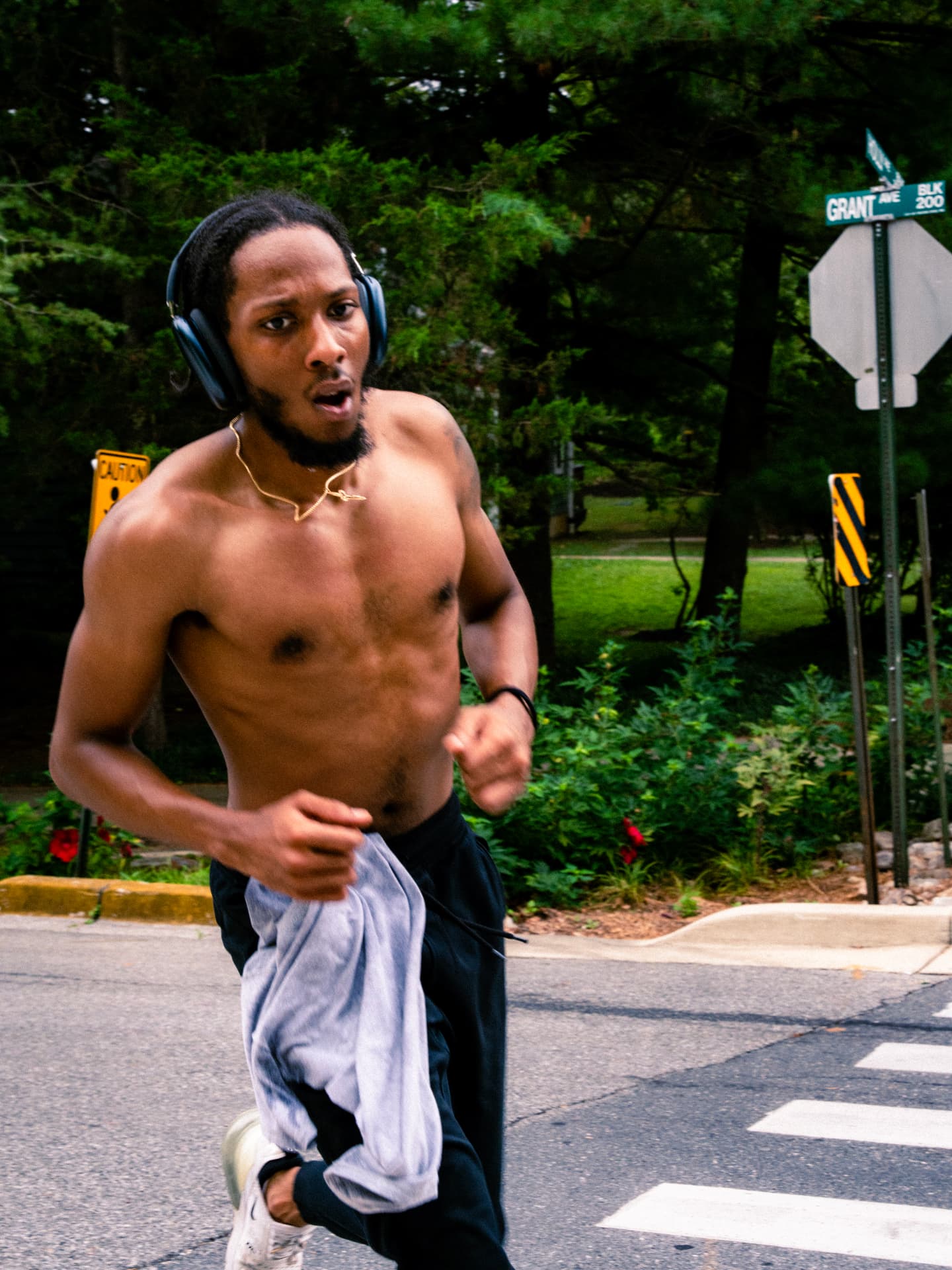 A shirtless runner in headphones pushing up Grant Ave