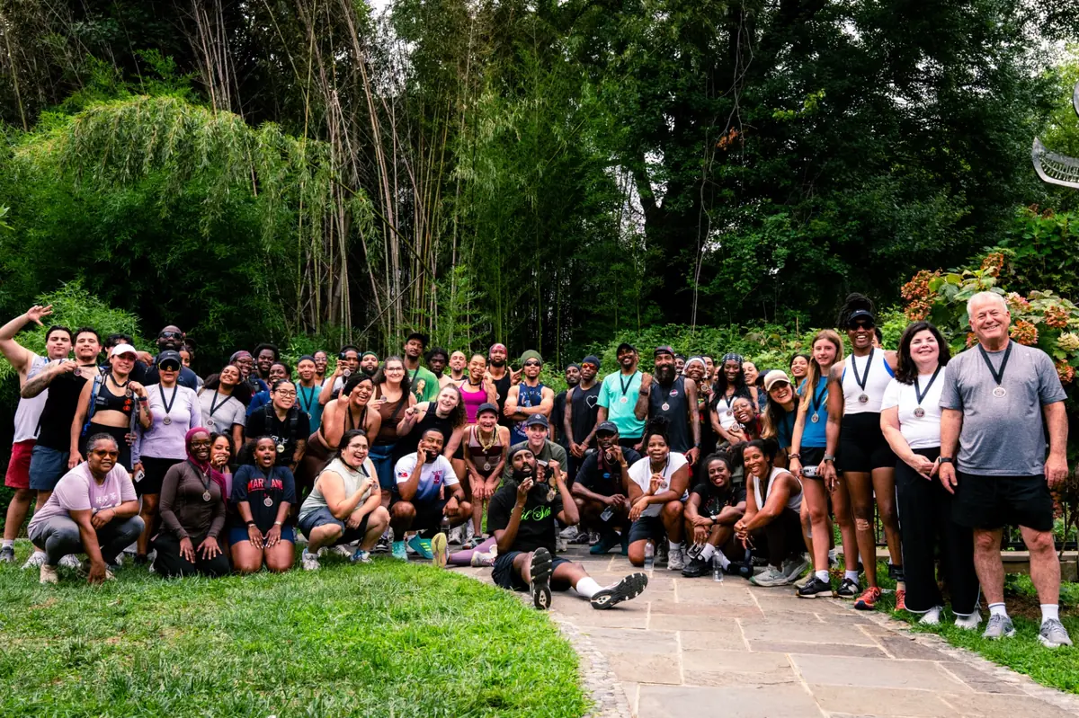 Run Takoma With Love finishers posing together with their medals in a Takoma Park garden