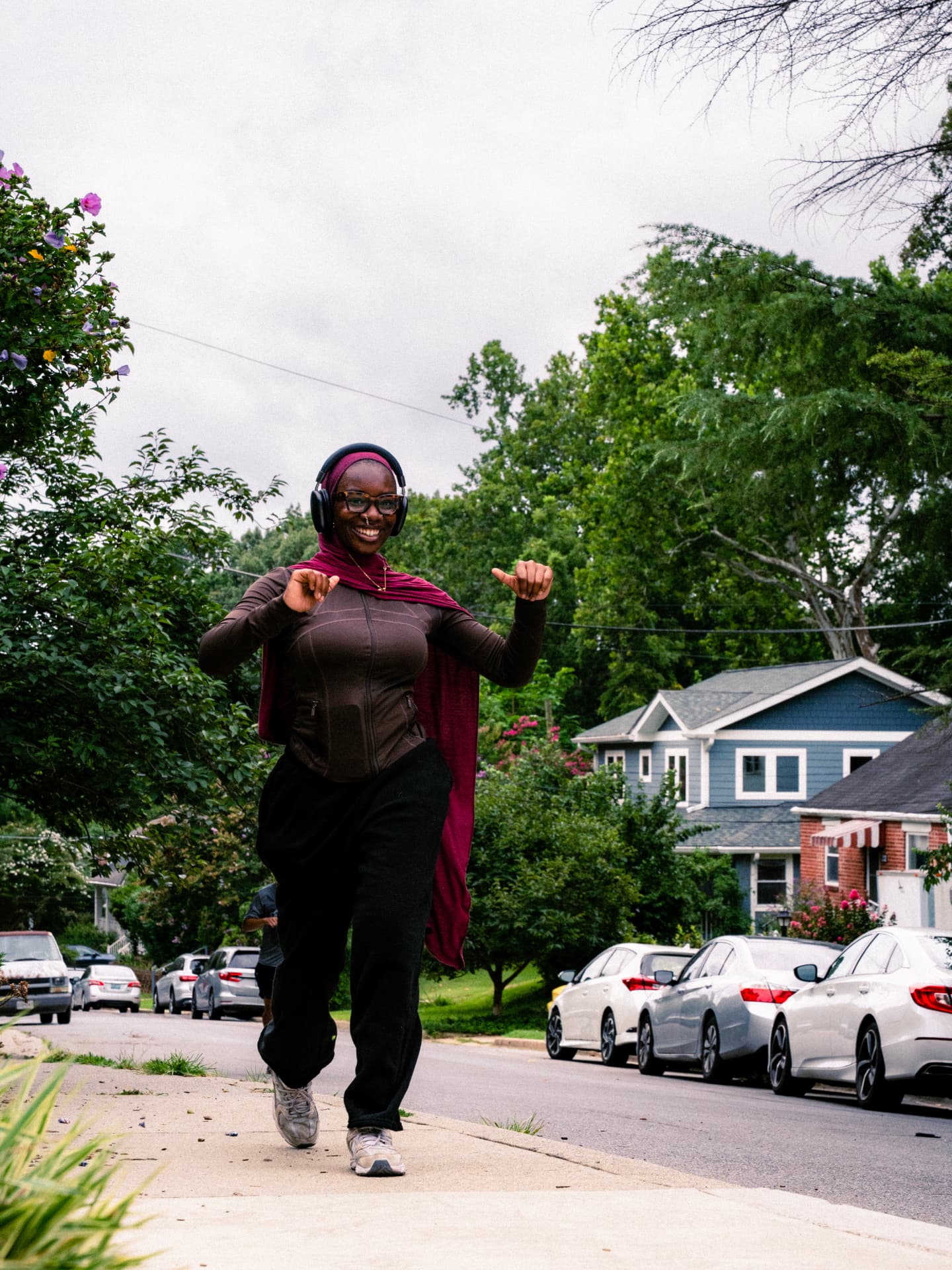 A runner in headphones and a hijab dancing down the sidewalk